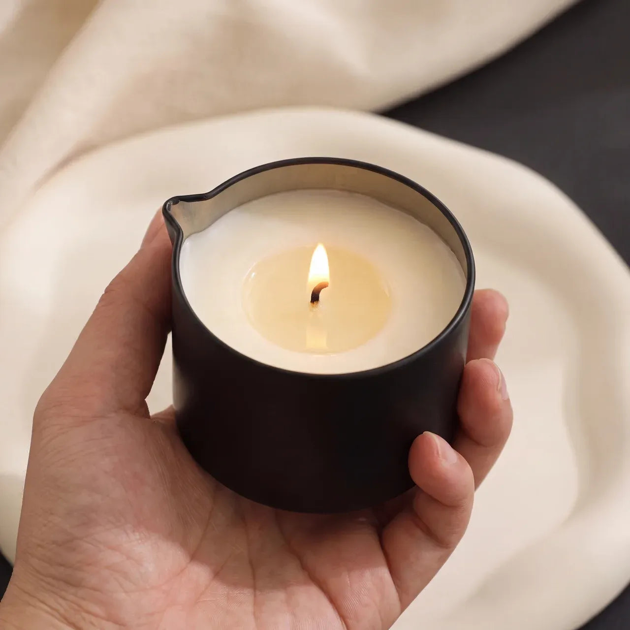 CareHush warming massage candle held in a hand
